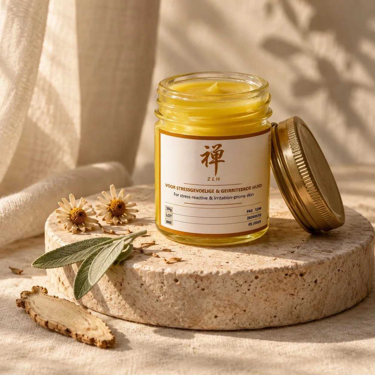 Zen Herbal Balm, a glass jar of golden balm with its lid off, on a travertine plinth with chamomile and sage
